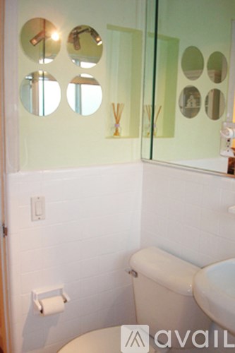 A bathroom with a toilet, sink and mirror.