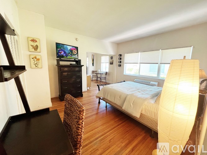 A bedroom with a bed, a chair, a cabinet, and a television.