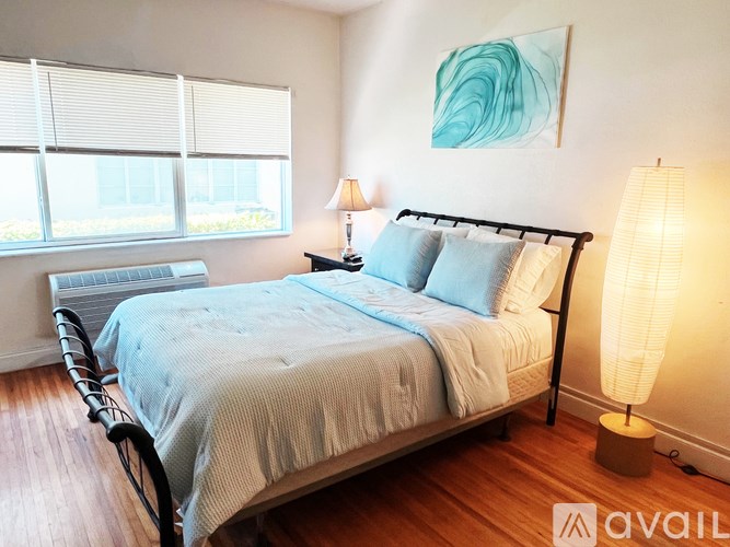 A bedroom with a bed, two lamps, and a painting on the wall.