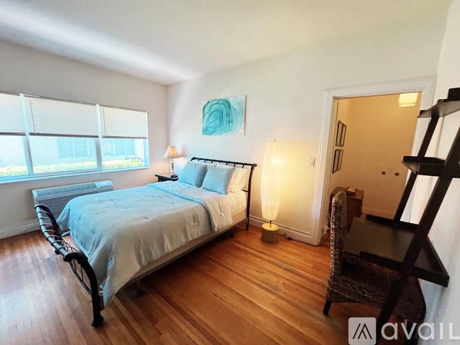 A bedroom with a large bed and a wooden floor.