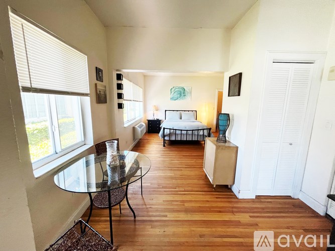 A bedroom with a bed, nightstand, and a window with blinds.