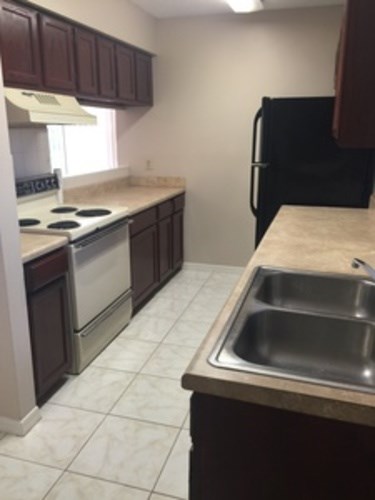 A kitchen with a stove, sink, and refrigerator.