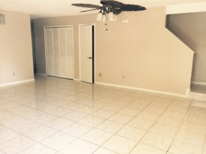 A room with a ceiling fan and tile flooring.