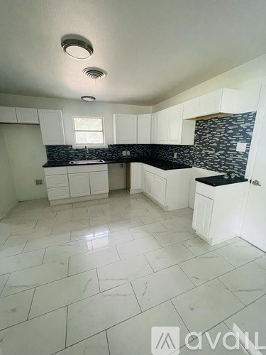 A kitchen with white cabinets and a black and white backsplash.