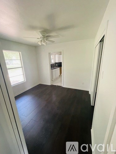 A room with a ceiling fan and wooden flooring.
