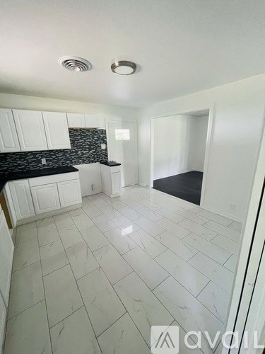 A kitchen with white cabinets and a black countertop.