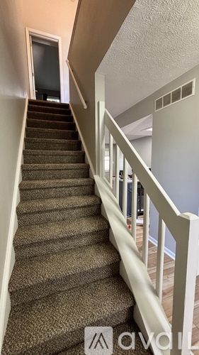 A staircase with a carpeted runner and white balusters.