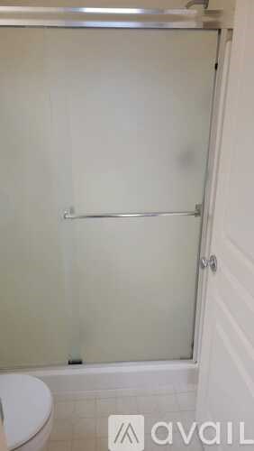 A white bathroom with a toilet and a glass shower door.