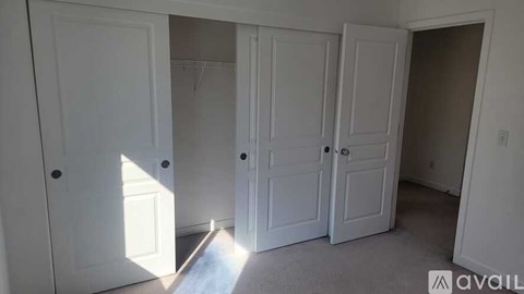 Three white doors in a room with sunlight shining through one of them.