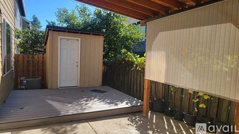 A small wooden shed with a white door is situated in a backyard.