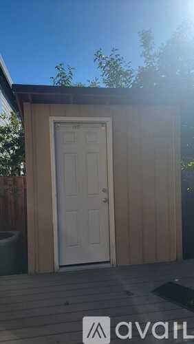 A wooden shed with a white door is in the backyard.