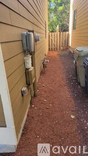 A narrow alley between two houses with a wooden fence on the right.