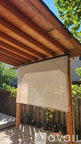 A wooden pergola with a white shade cloth over it.