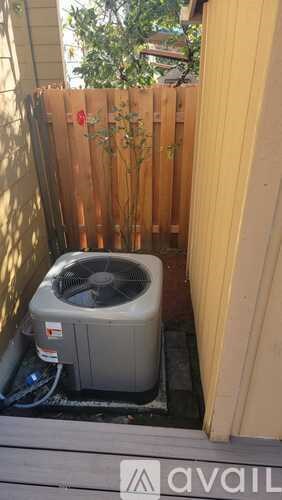 A small air conditioner unit is outside on a wooden deck.