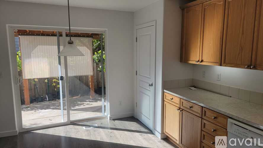 A kitchen with wooden cabinets and a sliding glass door leading to a backyard.