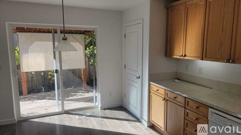 A kitchen with wooden cabinets and a sliding glass door leading to a backyard.