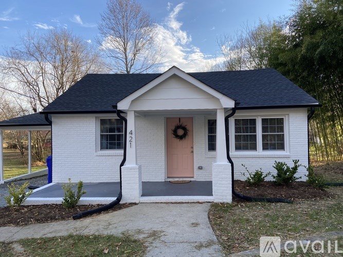 A small white house with a black roof and a pink door.