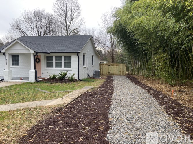 A white house with a gravel path leading to it.