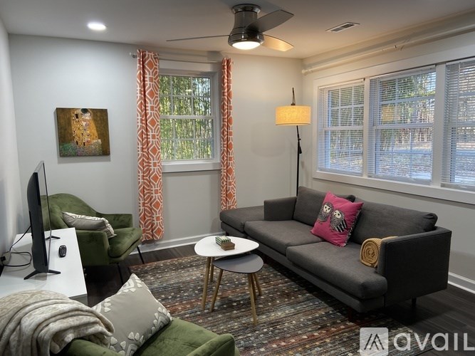 A living room with a grey couch, a green chair, a coffee table, and a painting on the wall.