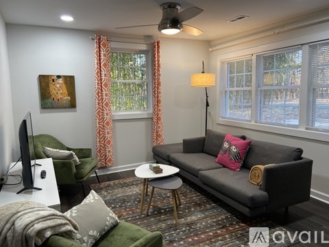 A living room with a grey couch, a green chair, a coffee table, and a painting on the wall.