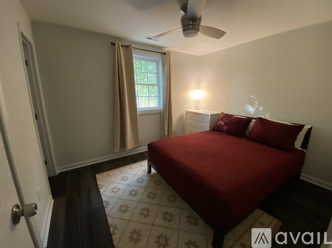 A bedroom with a red bed and a ceiling fan.