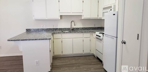 A kitchen with white cabinets and a granite countertop.