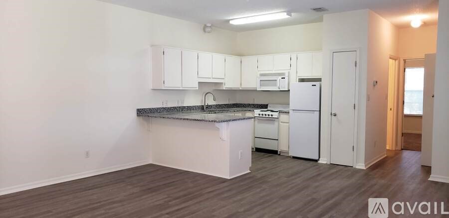 A kitchen with white cabinets and appliances in a room with wood flooring.