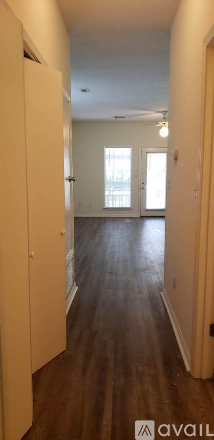 A long hallway with a door on the left and a window on the right.