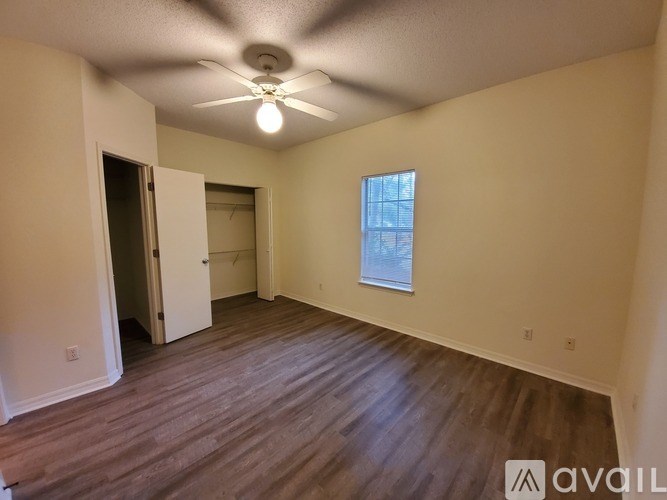 A room with a ceiling fan and a window with a view of a building outside.