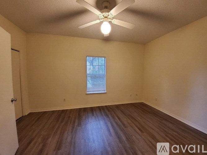 A room with a ceiling fan and wooden flooring.