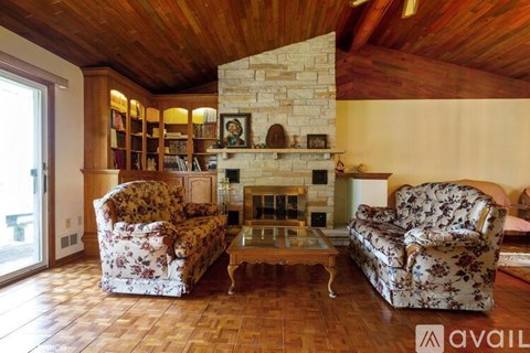 A living room with two floral patterned chairs and a stone fireplace.