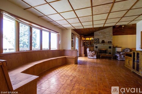 A living room with a stone fireplace and wooden floors.