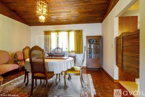 A wooden table with chairs and a sofa in a room with a wooden ceiling.