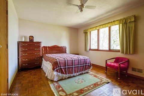 A bedroom with a bed, chair, and rug.