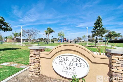 A sign that says Garden City Acres Park in front of a playground.