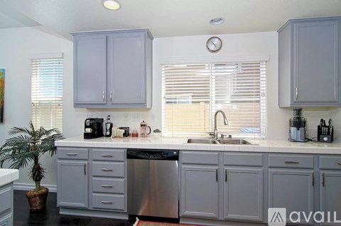 A kitchen with a stainless steel dishwasher and a clock on the wall.