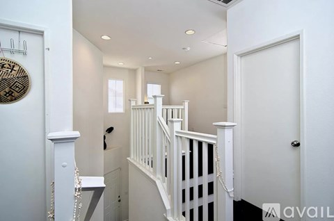 A white staircase with a rope railing and a white door.