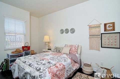 A bedroom with a bed, a lamp, and a wall hanging.