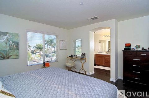 A bedroom with a large bed and a desk with a chair.