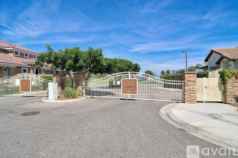 A gated entrance to a residential area with houses on either side.