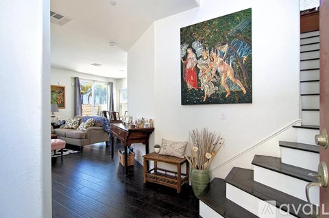 A painting of a woman and two children is hanging on a white wall above a wooden table.