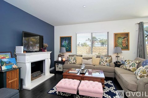 A living room with a fireplace, couches, and artwork on the walls.