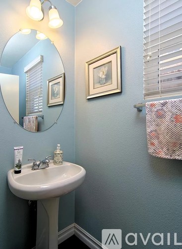 A bathroom with a sink, mirror, and two pictures on the wall.