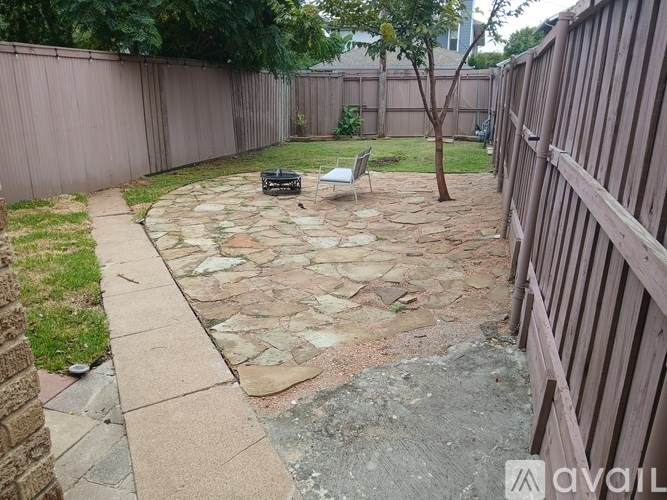 A backyard with a stone patio and a wooden fence.