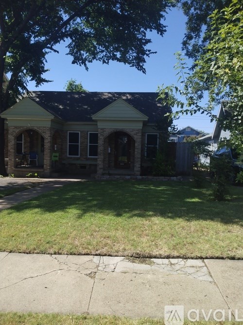 A house with a green lawn and a cracked sidewalk in front.