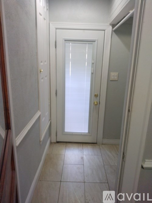 A white door is in a hallway with a tiled floor.