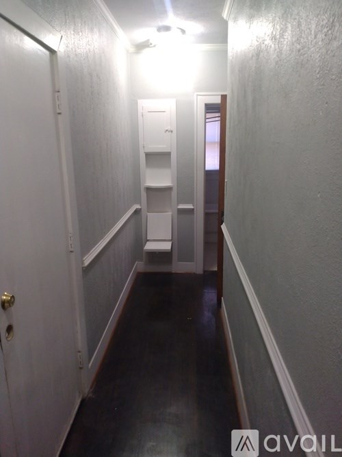 A hallway with a door on the left and a door with a window on the right.