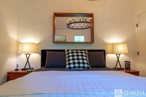 A bedroom with a bed, two lamps, and a mirror on the wall.