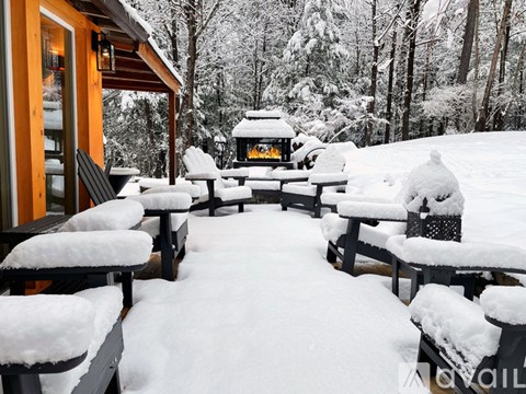 A snow-covered picnic area with a fire pit in the middle.