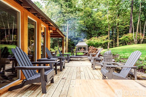 A wooden deck with chairs and a gazebo in a lush green forest.